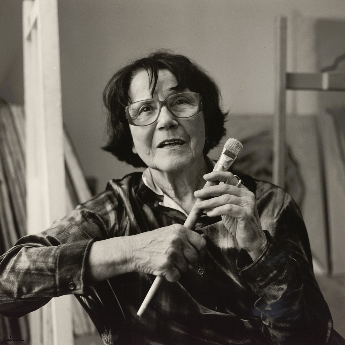 Portrait photography of Maria Lassnig holding a brush in her hand and looking into the camera