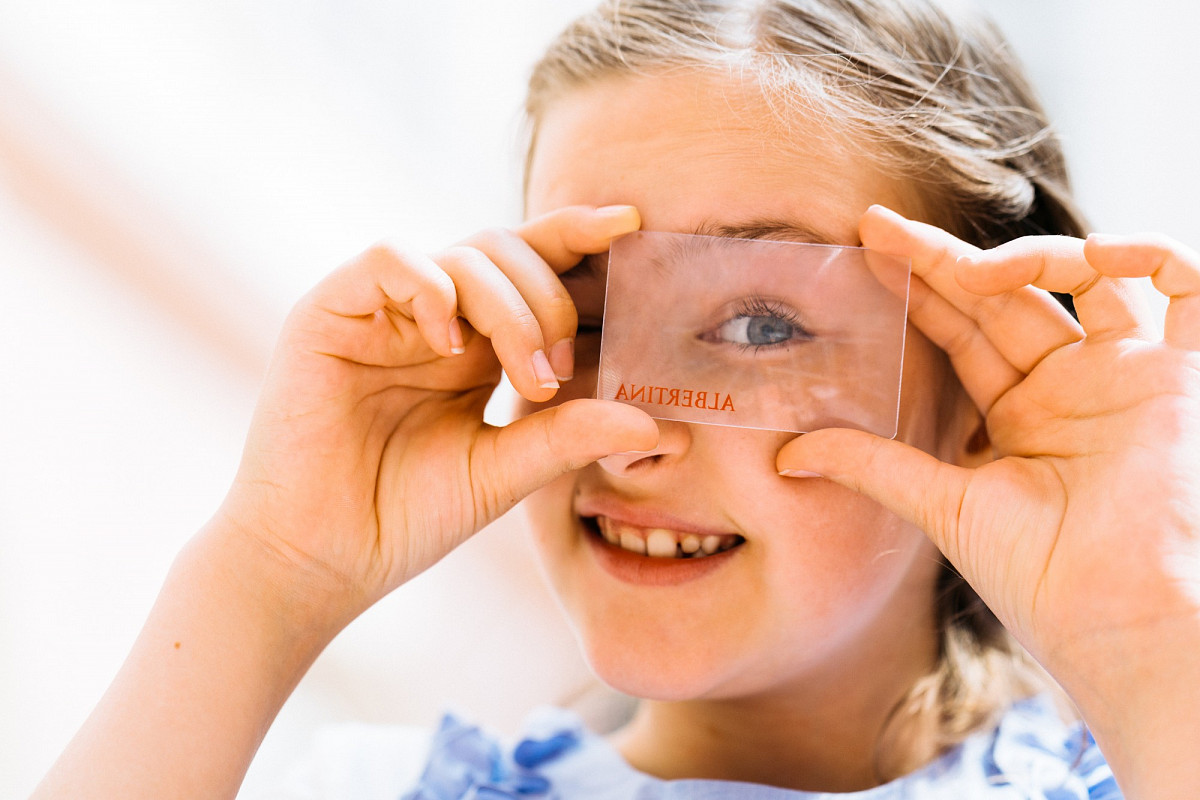 Kind schaut durch eine Glasscheibe mit der Aufschrift "Albertina" | Foto © Marko Mestrovic