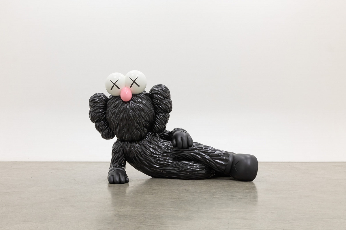Skulptur einer seitlich aufgestützt, liegenden, schwarz pelzigen Comicfigur mit einer pinken Stupsnase und X-Augen.