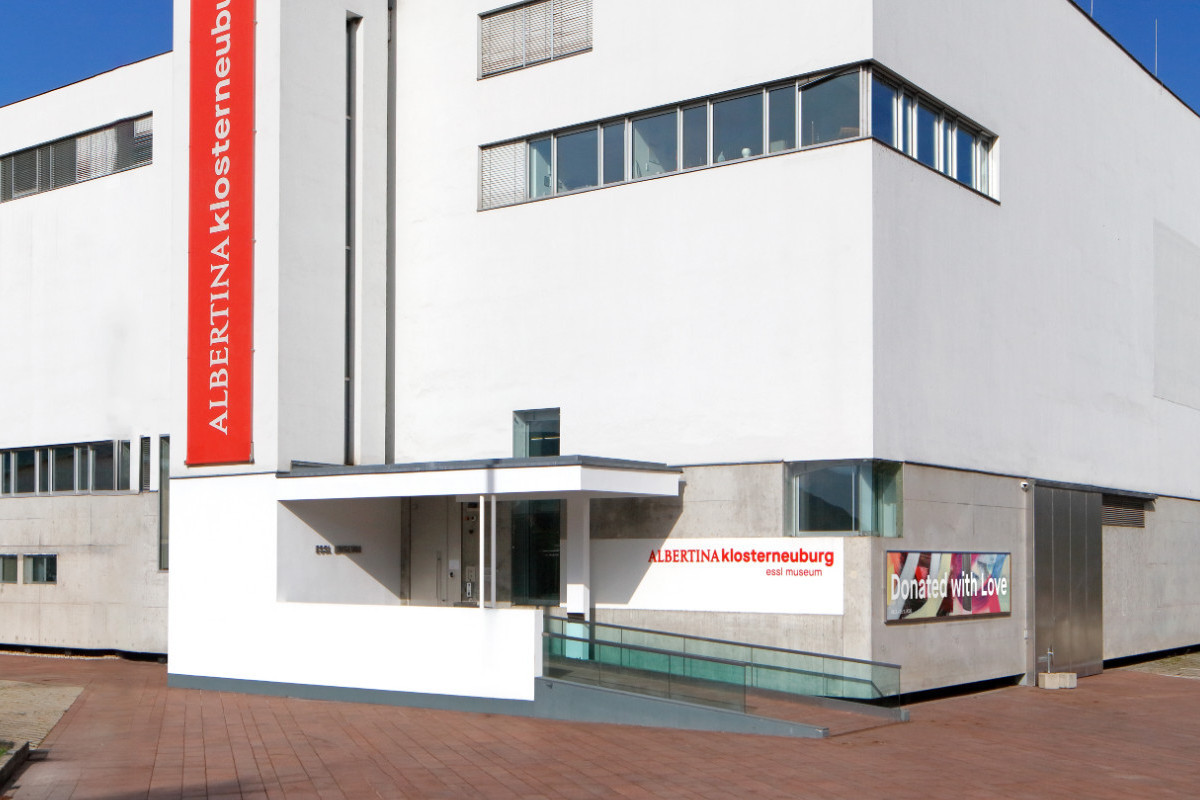 Weißes, modernes Gebäude von außen mit rotem Schriftzug ALBERTINA KLOSTERNEUBURG. Credit: Foto © Rainer Iglar