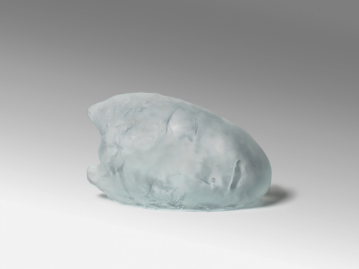 Ein Kopf aus Glas, seitlich liegend. Man erkennt ein Gesicht.