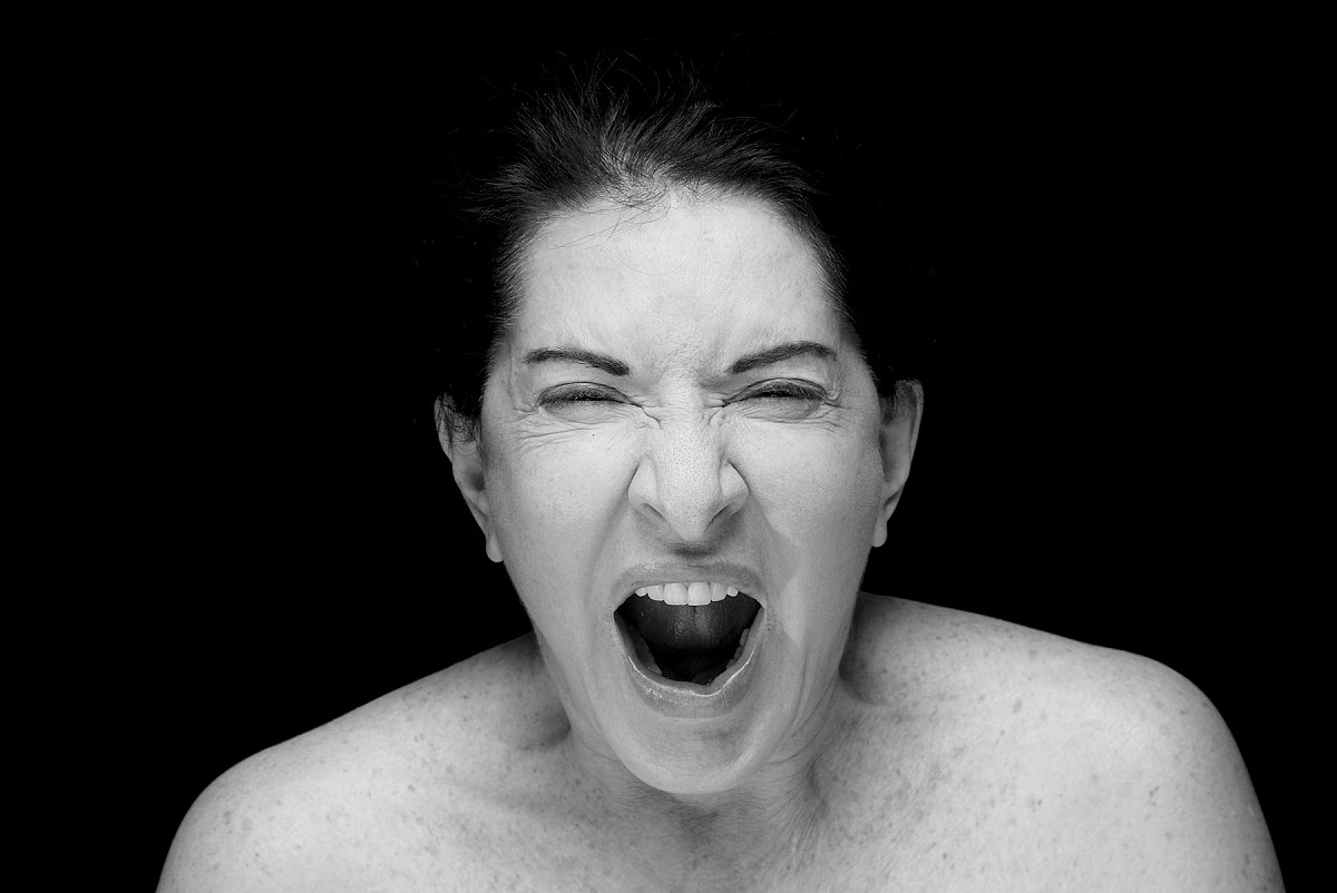 Black and white portrait of the artist, showing her screaming with her mouth open.