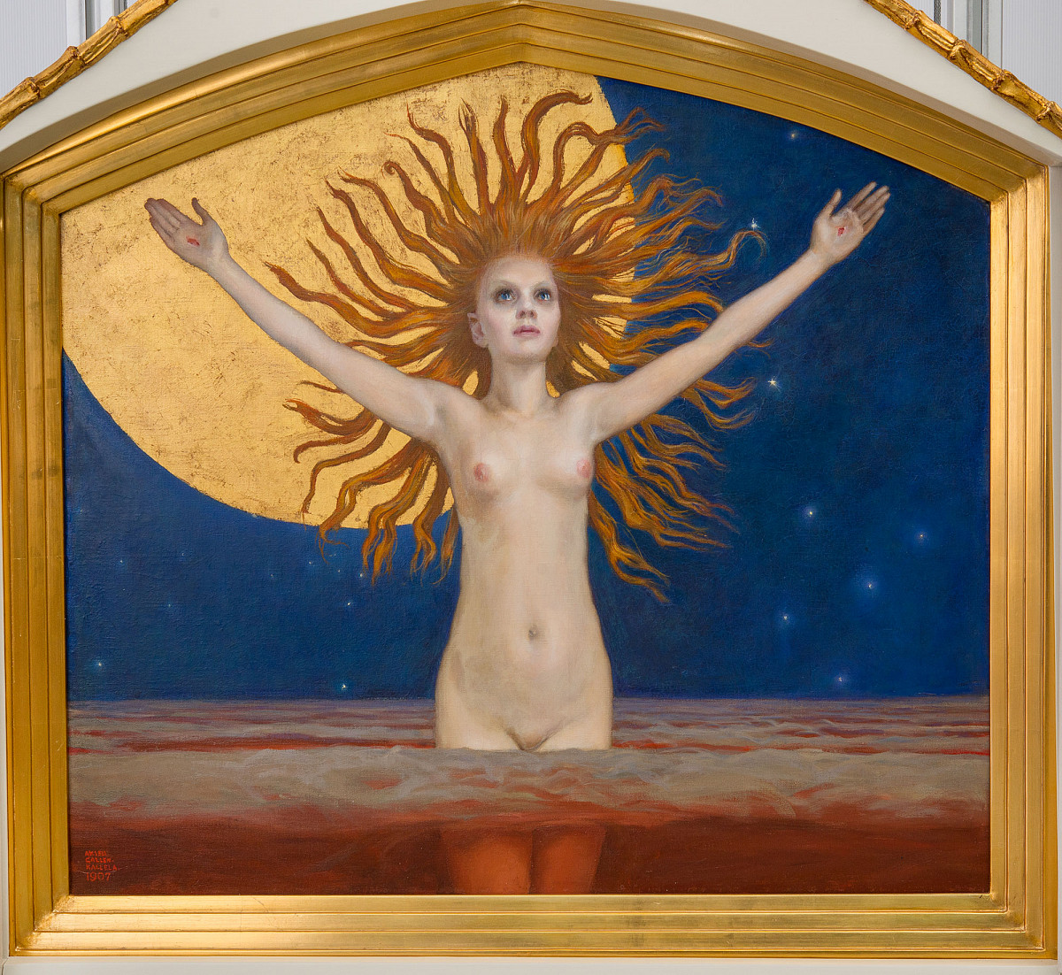A naked young woman stands with her arms raised and her gaze fixed on the reddish water. Her long red hair flows around her head like a wreath. In the background, a blue night sky can be seen with a large golden moon.
