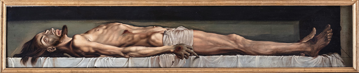 The body of Jesus laid out on a bed covered with a white sheet.