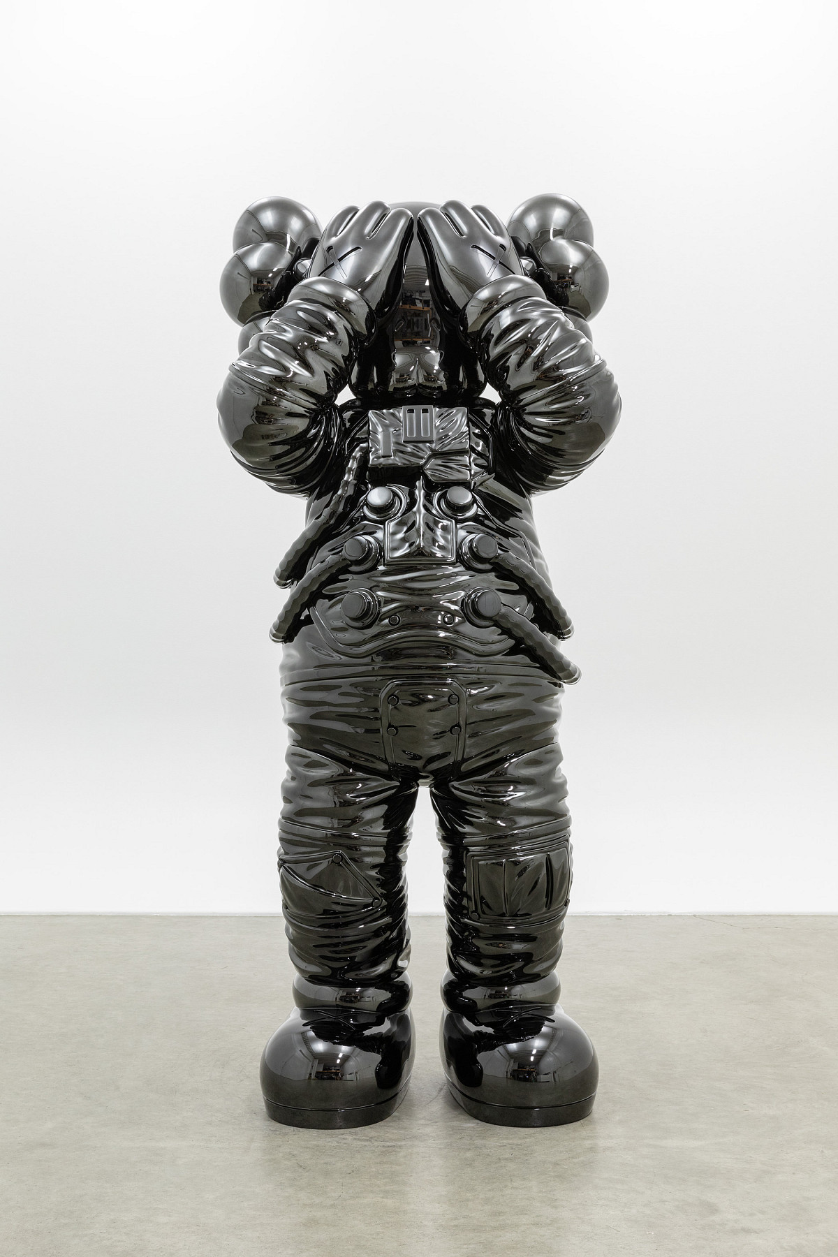 Sculpture of a black comic book character in a space suit, holding his hands in front of his eyes.