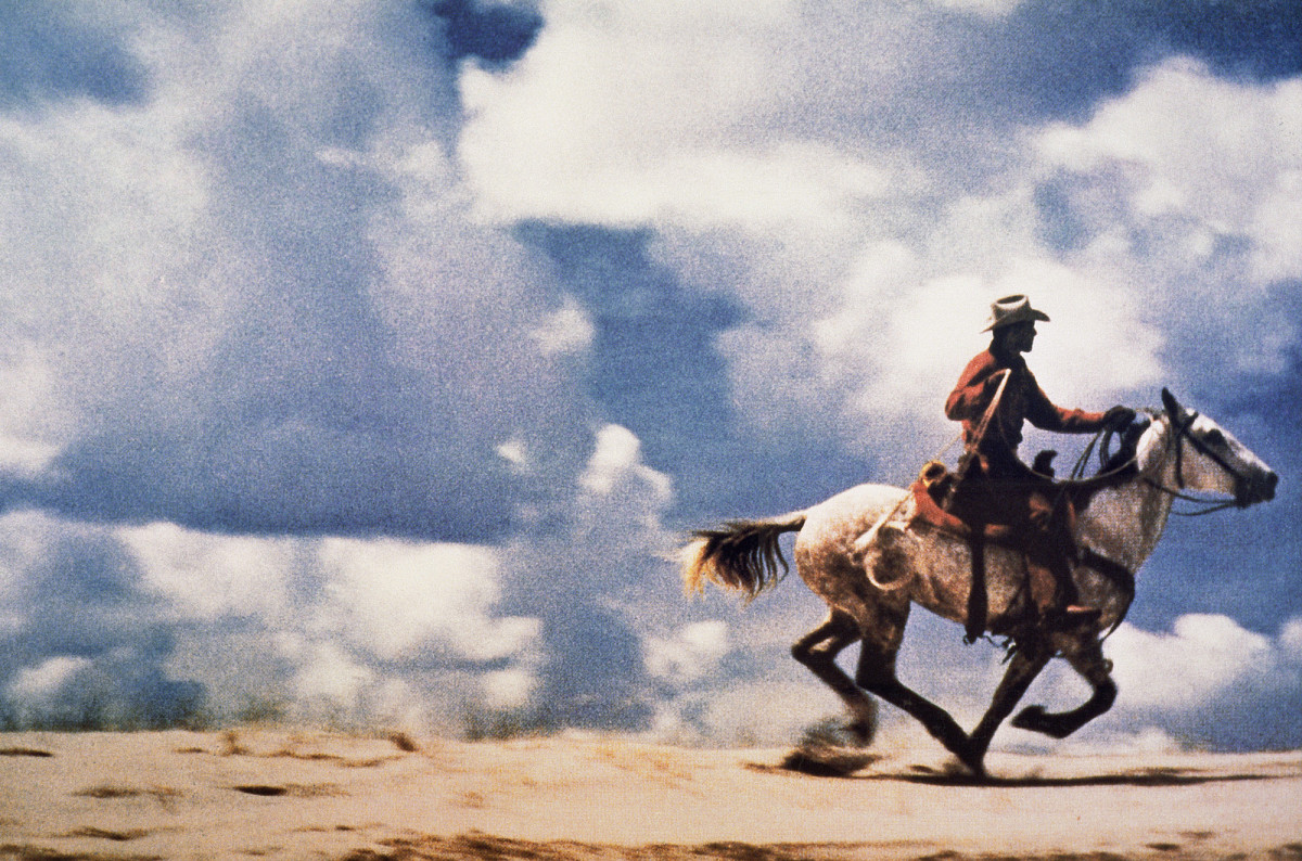 Farbfotografie eines Cowboys auf einem galoppierenden Pferd in weiter Landschaft; großformatiger, horizontaler Bildausschnitt. Credit: Richard Prince | Untitled (Cowboy), 1989 | Courtesy of Richard Prince Studio © Richard Prince